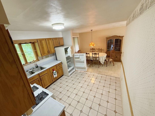 717 King St, Mckeesport, PA 15132 - kitchen with light countertops, brown cabinetry, hanging light fixtures, light flooring, and wallpapered walls