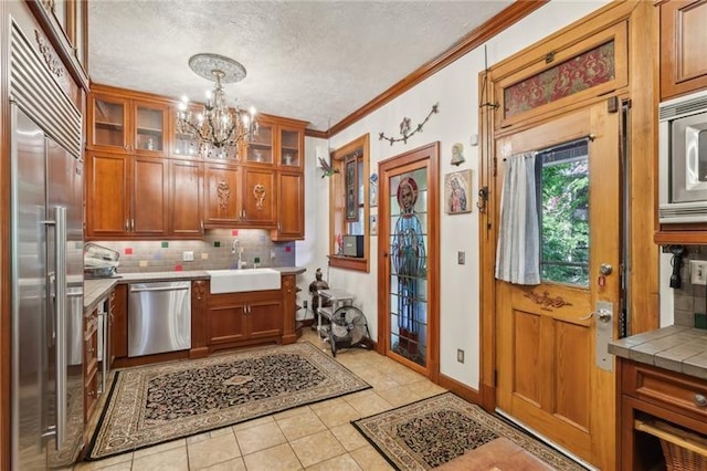 221 E Moody Ave, New Castle/2Nd, PA 16101 - kitchen featuring built in appliances, a chandelier, decorative backsplash, brown cabinets, and ornamental molding