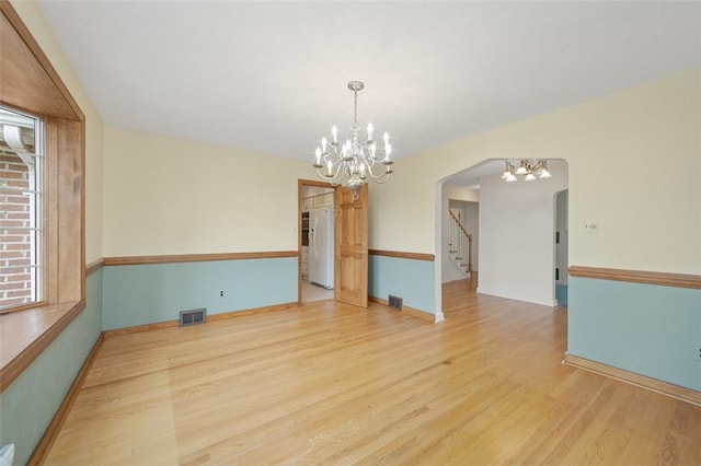 126 Elm Dr, Level Green, PA 15085 - empty room featuring a chandelier, arched walkways, wood finished floors, and stairs