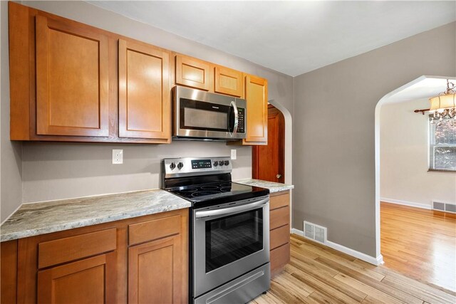 129 Temona Dr, Pleasant Hills, PA 15236 - kitchen with stainless steel appliances, arched walkways, light wood finished floors, and brown cabinets