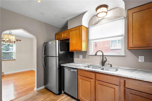 129 Temona Dr, Pleasant Hills, PA 15236 - kitchen featuring appliances with stainless steel finishes, light wood-style floors, a chandelier, arched walkways, and brown cabinetry