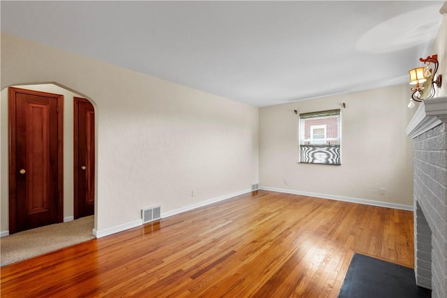 129 Temona Dr, Pleasant Hills, PA 15236 - spare room featuring a brick fireplace, arched walkways, and wood finished floors