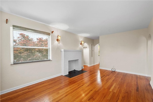 129 Temona Dr, Pleasant Hills, PA 15236 - unfurnished living room with arched walkways, wood finished floors, and a brick fireplace