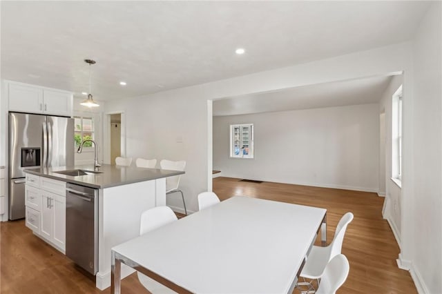 221 Miller Ave, Duquesne, PA 15110 - kitchen featuring stainless steel appliances, an island with sink, wood finished floors, a kitchen bar, and white cabinetry