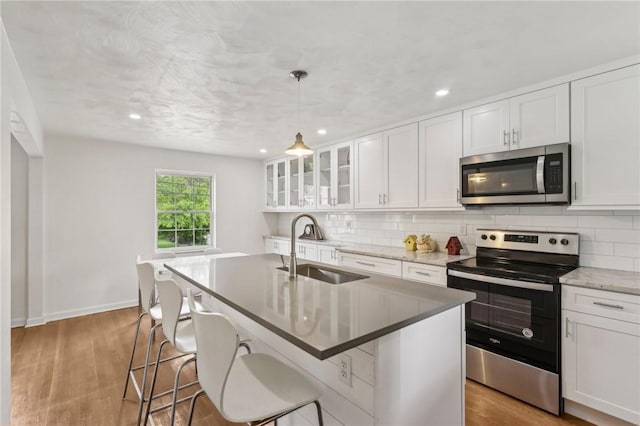221 Miller Ave, Duquesne, PA 15110 - kitchen with stainless steel appliances, light wood-style flooring, decorative backsplash, an island with sink, and recessed lighting