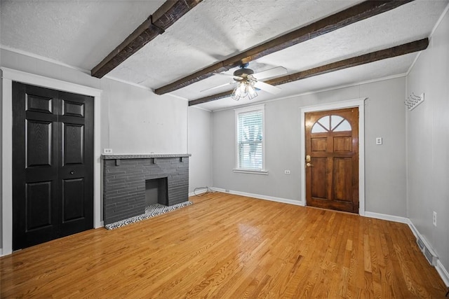 4829 Hatfield St, Lawrenceville, PA 15201 - unfurnished living room featuring wood finished floors, a brick fireplace, ceiling fan, beamed ceiling, and a textured ceiling