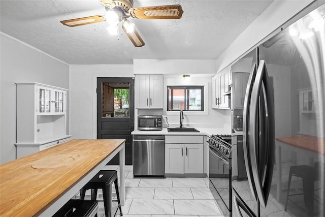4829 Hatfield St, Lawrenceville, PA 15201 - kitchen featuring appliances with stainless steel finishes, a textured ceiling, light countertops, ceiling fan, and light marble finish floors
