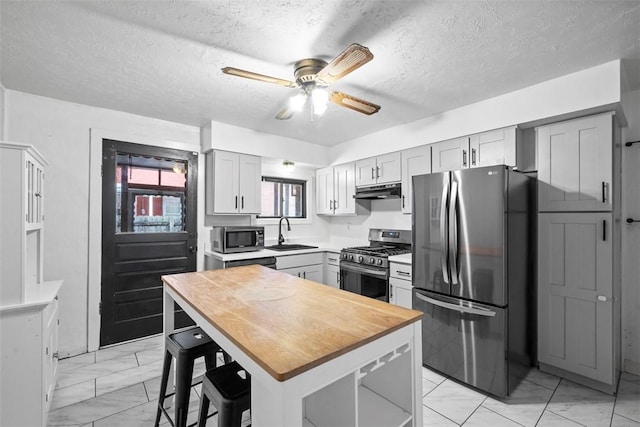 4829 Hatfield St, Lawrenceville, PA 15201 - kitchen featuring stainless steel appliances, light marble finish floors, a ceiling fan, under cabinet range hood, and a textured ceiling