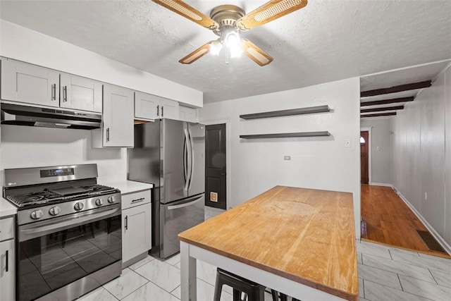 4829 Hatfield St, Lawrenceville, PA 15201 - kitchen featuring under cabinet range hood, stainless steel appliances, light marble finish flooring, a ceiling fan, and a textured ceiling