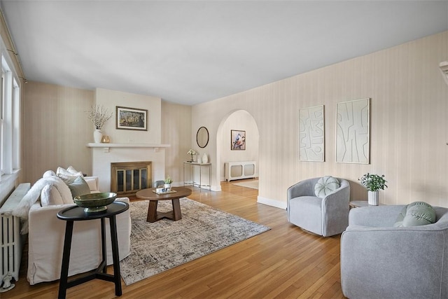 4035 Ludwick St, Squirrel Hill, PA 15217 - living area with wallpapered walls, wood finished floors, arched walkways, a glass covered fireplace, and radiator