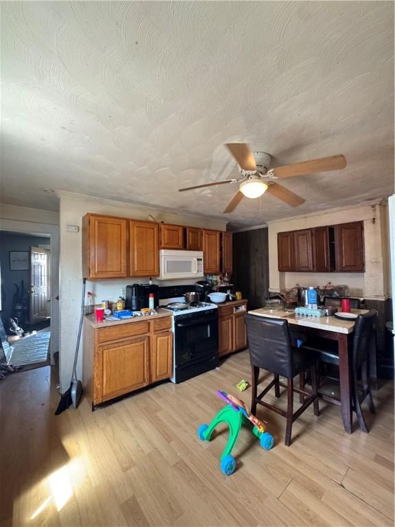 200 Jarvis St, Aliquippa, PA 15001 - kitchen with white microwave, range with electric stovetop, light wood-type flooring, ceiling fan, and brown cabinets