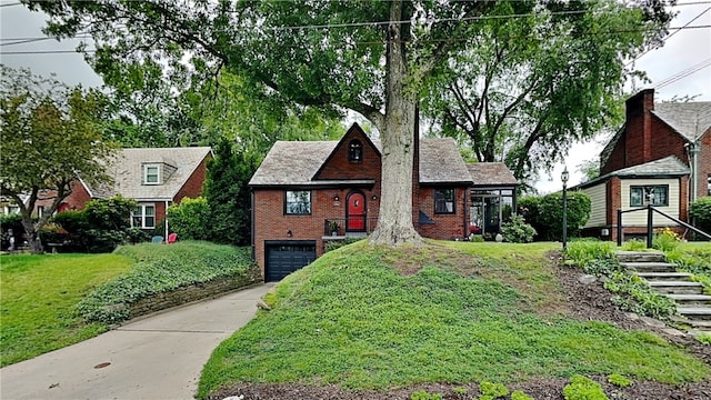 217 Monroe Dr, Ross Twp, PA 15229 - tudor house featuring an attached garage, brick siding, concrete driveway, and a front lawn
