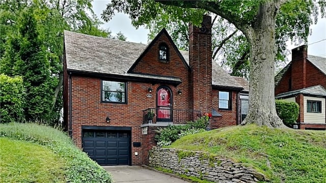 217 Monroe Dr, Ross Twp, PA 15229 - english style home featuring a chimney, brick siding, concrete driveway, and a garage