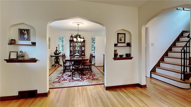 217 Monroe Dr, Ross Twp, PA 15229 - dining area featuring wood finished floors, a chandelier, stairway, and arched walkways