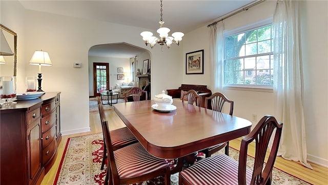 217 Monroe Dr, Ross Twp, PA 15229 - dining room featuring arched walkways, healthy amount of natural light, light wood finished floors, and a chandelier