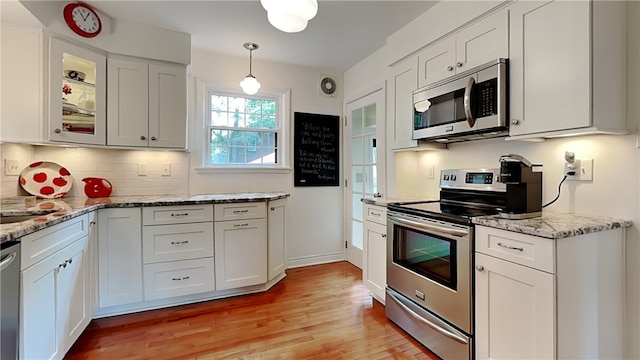 217 Monroe Dr, Ross Twp, PA 15229 - kitchen with stainless steel appliances, light wood-style floors, tasteful backsplash, white cabinetry, and glass insert cabinets