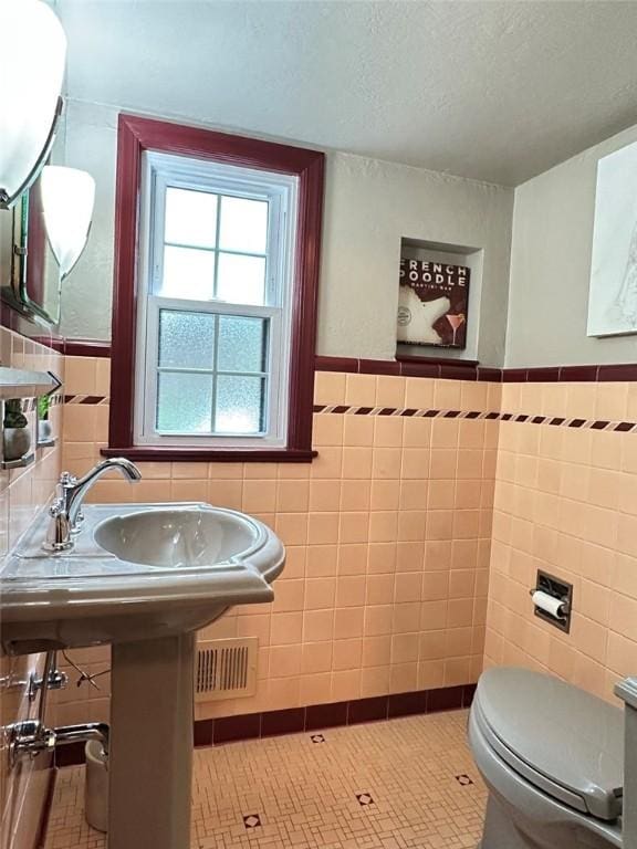 217 Monroe Dr, Ross Twp, PA 15229 - half bathroom with tile walls, a textured ceiling, a wainscoted wall, and tile patterned floors