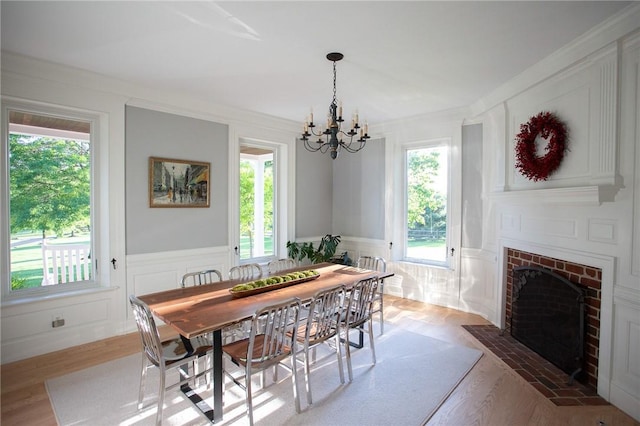 255 Camp Run Rd, Lancaster Twp, PA 16037 - dining room featuring a chandelier, healthy amount of natural light, a wainscoted wall, a brick fireplace, and light wood-type flooring