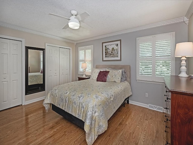406 Country View Dr, Lower Burrell, PA 15068 - bedroom featuring wood finished floors, two closets, a textured ceiling, crown molding, and ceiling fan