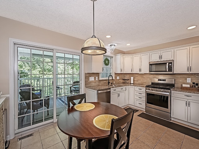 406 Country View Dr, Lower Burrell, PA 15068 - kitchen with stainless steel appliances, light tile patterned flooring, decorative backsplash, a textured ceiling, and pendant lighting