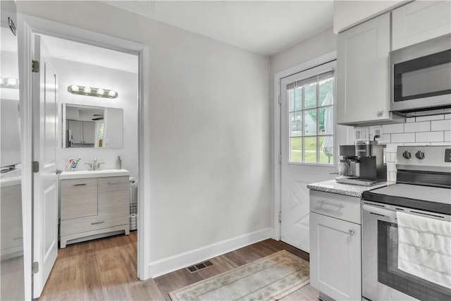 18 Allegheny Ave, South Fayette, PA 15031 - kitchen with stainless steel appliances, light wood-type flooring, tasteful backsplash, and white cabinetry