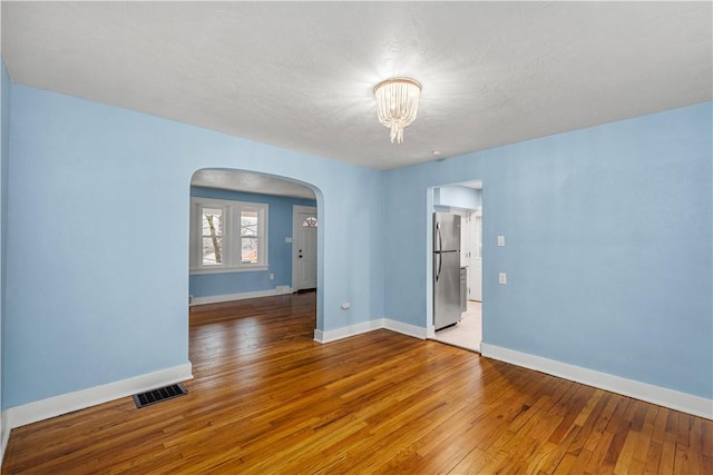 2301 Fairland St, Overbrook, PA 15210 - spare room featuring arched walkways, wood-type flooring, and a chandelier