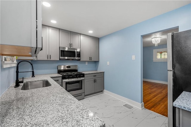 2301 Fairland St, Overbrook, PA 15210 - kitchen with appliances with stainless steel finishes, gray cabinets, light marble finish floors, recessed lighting, and light stone countertops