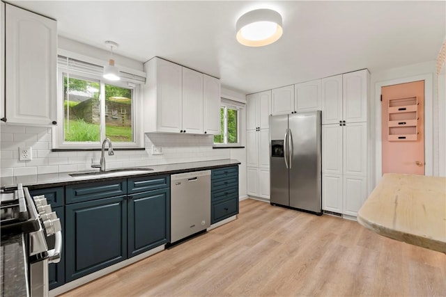 601 4th St, Penn Hills, PA 15147 - kitchen featuring appliances with stainless steel finishes, white cabinetry, tasteful backsplash, light wood-type flooring, and dark countertops
