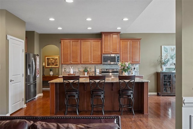743 Packsaddle Trl, Richland, PA 15044 - kitchen featuring stainless steel appliances, dark wood finished floors, backsplash, a center island with sink, and light stone countertops