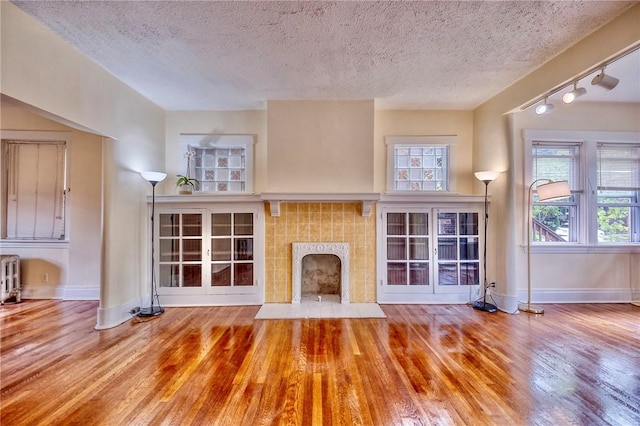2267 Tilbury Ave, Squirrel Hill, PA 15217 - unfurnished living room featuring wood finished floors, a fireplace, radiator heating unit, track lighting, and a textured ceiling