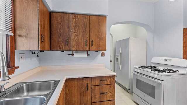 304 Wylie Ave, Elizabeth Twp/Boro, PA 15037 - kitchen with white appliances, brown cabinetry, light countertops, light flooring, and arched walkways