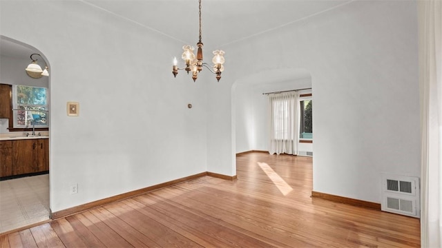 304 Wylie Ave, Elizabeth Twp/Boro, PA 15037 - unfurnished dining area with arched walkways, light wood finished floors, and a chandelier