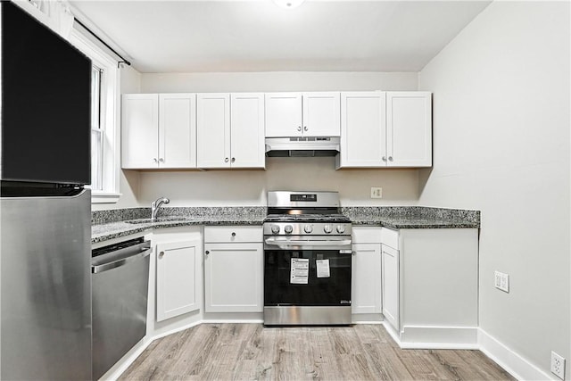 1334 Franklin Ave, Wilkinsburg, PA 15221 - kitchen featuring appliances with stainless steel finishes, under cabinet range hood, light wood finished floors, white cabinetry, and dark stone counters