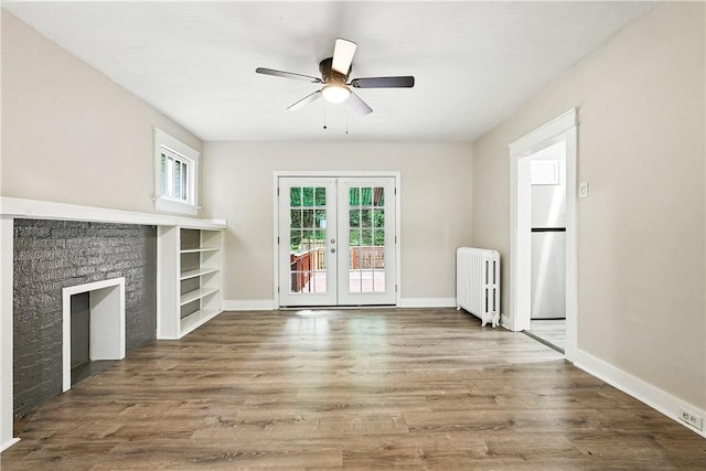 1334 Franklin Ave, Wilkinsburg, PA 15221 - unfurnished living room featuring radiator heating unit, french doors, a ceiling fan, a fireplace, and wood finished floors