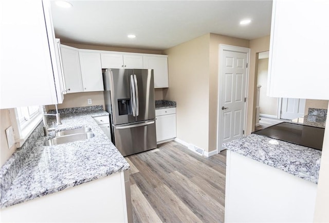 1451 W Pittsburgh St, East Huntingdon, PA 15683 - kitchen featuring stainless steel fridge, white cabinets, light wood-type flooring, light stone countertops, and recessed lighting