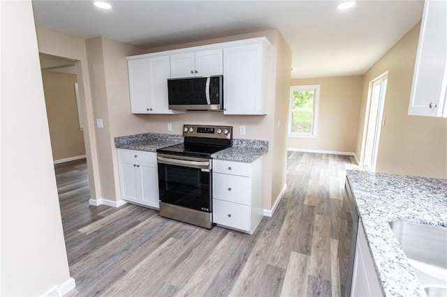 1451 W Pittsburgh St, East Huntingdon, PA 15683 - kitchen with stainless steel appliances, light wood-style flooring, white cabinets, recessed lighting, and light stone countertops