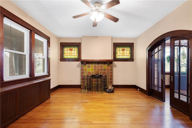 512 Gorgas St, Arlington, PA 15210 - unfurnished living room with arched walkways, radiator heating unit, a tiled fireplace, and light wood finished floors