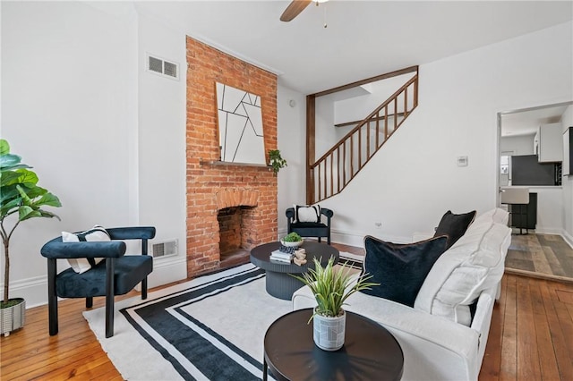 3817 Howley St, Lawrenceville, PA 15201 - living area featuring hardwood / wood-style floors, a brick fireplace, stairs, and ceiling fan