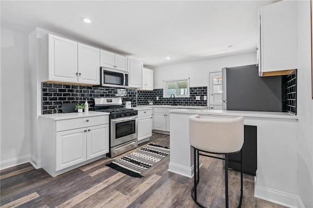 3817 Howley St, Lawrenceville, PA 15201 - kitchen featuring stainless steel appliances, decorative backsplash, light countertops, white cabinetry, and dark wood-type flooring