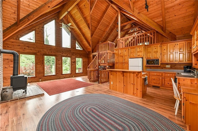 117 Oak Dr, Forward Twp But, PA 16033 - kitchen with black microwave, freestanding refrigerator, a wood stove, a wooden ceiling with exposed beams, and light wood-type flooring