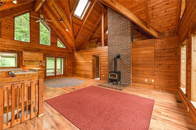 117 Oak Dr, Forward Twp But, PA 16033 - unfurnished living room featuring wooden walls, a wood stove, light wood-style floors, high vaulted ceiling, and a wood ceiling with exposed beams