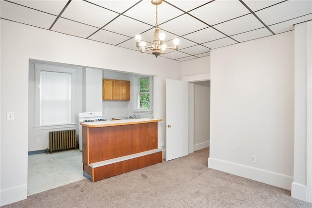 97 N Euclid Ave, Bellevue, PA 15202 - kitchen with radiator, light carpet, a chandelier, white gas range, and brown cabinetry