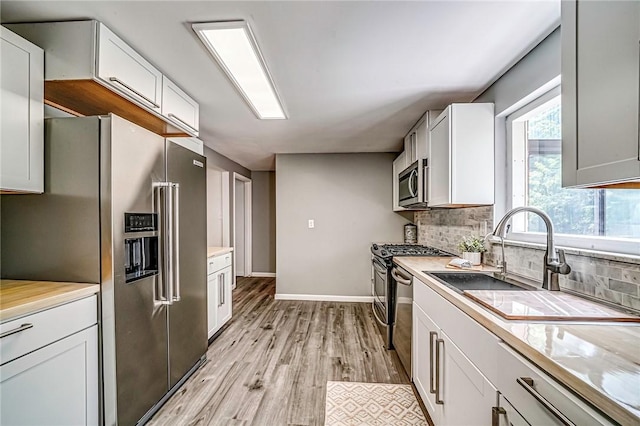 150 Dover Dr, Moon/Crescent Twp, PA 15108 - kitchen with appliances with stainless steel finishes, decorative backsplash, light wood-style flooring, white cabinets, and light countertops