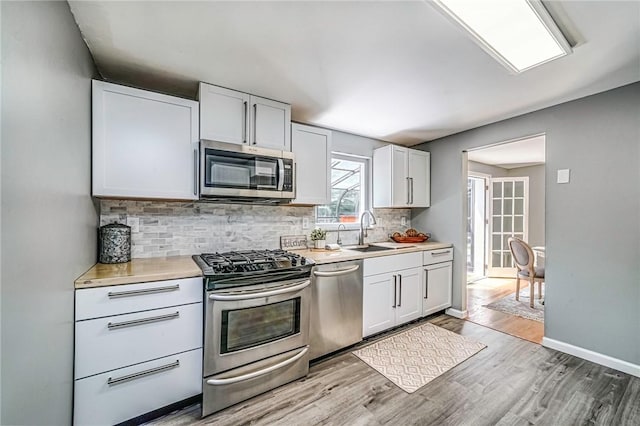 150 Dover Dr, Moon/Crescent Twp, PA 15108 - kitchen featuring appliances with stainless steel finishes, light countertops, backsplash, light wood finished floors, and white cabinets