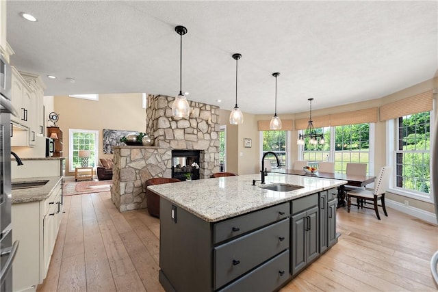 548 Lang Rd, Sewickley Heights, PA 15143 - kitchen with white cabinetry, light wood finished floors, a center island with sink, a fireplace, and recessed lighting