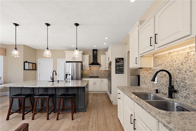 548 Lang Rd, Sewickley Heights, PA 15143 - kitchen featuring wall chimney range hood, appliances with stainless steel finishes, tasteful backsplash, white cabinetry, and light wood finished floors