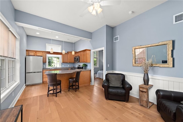 548 Lang Rd, Sewickley Heights, PA 15143 - kitchen with appliances with stainless steel finishes, open floor plan, brown cabinets, a breakfast bar, and a kitchen island