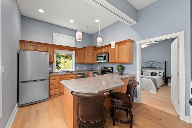 548 Lang Rd, Sewickley Heights, PA 15143 - kitchen featuring appliances with stainless steel finishes, light wood finished floors, a peninsula, pendant lighting, and a high ceiling