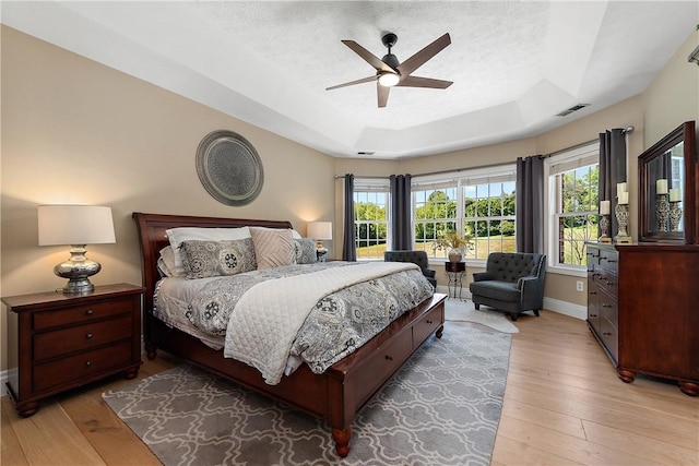 548 Lang Rd, Sewickley Heights, PA 15143 - bedroom featuring a tray ceiling, light wood finished floors, multiple windows, a textured ceiling, and ceiling fan