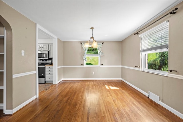 345 Franklin Dr, Peters Twp, PA 15241 - unfurnished dining area with arched walkways, light wood-style floors, and a chandelier